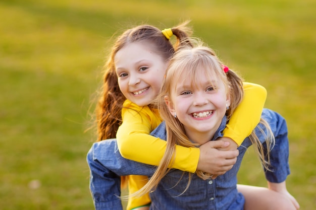 Zdjęcie portret dwóch szczęśliwych uroczych dziewcząt na świeżym powietrzu w parku, zabawy dzieci