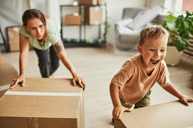 Zdjęcie portret dwóch wesołych chłopców, którzy przenoszą pudełka, podczas gdy rodzina przenosi się do nowego domu