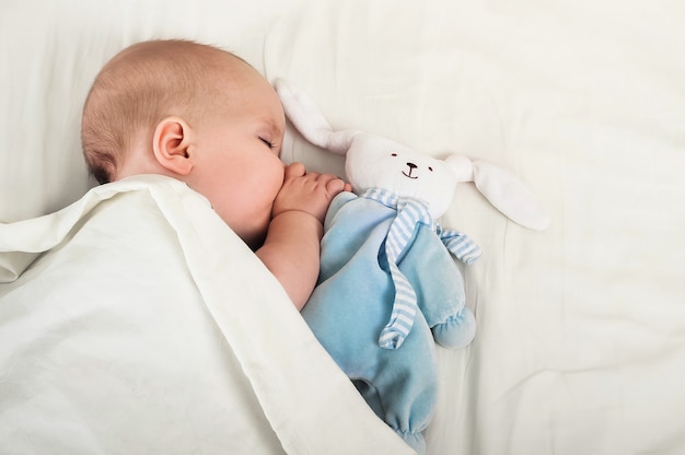 Portret dziecka 6 miesięcy śpi z zając zabawka. Maluch, ząbkowanie, koncepcja snu dziecka.