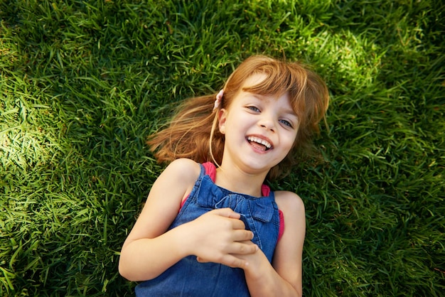 Portret dziecka i trawa z uśmiechem lub powyżej na wypoczynek na wsi na wakacje letnie przyroda lub park Dzieci szkolne twarze i szczęśliwe w Kalifornii środowisko do śmiechu słońca lub łąki