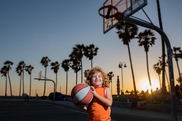 Portret dziecka koszykarza dziecko trzyma piłkę do koszykówki na boisku do koszykówki na plaży w Wenecji