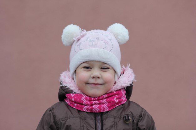 Portret dziecka w ciepłym ubraniu w sezonie zimowym, patrząc na bok na fioletowym tle
