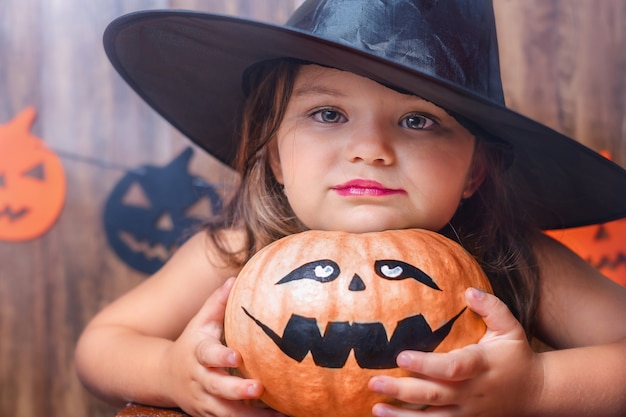 Portret dziecka w kapeluszu wiedźmy z dynią na halloween