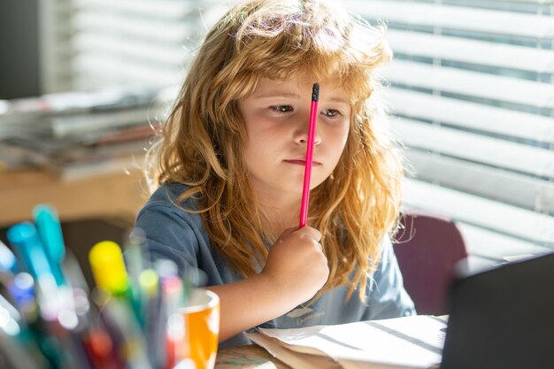 Portret dziecko w wieku szkolnym siedzi na stole odrabiania lekcji uczeń robi notatki w zeszycie podczas online