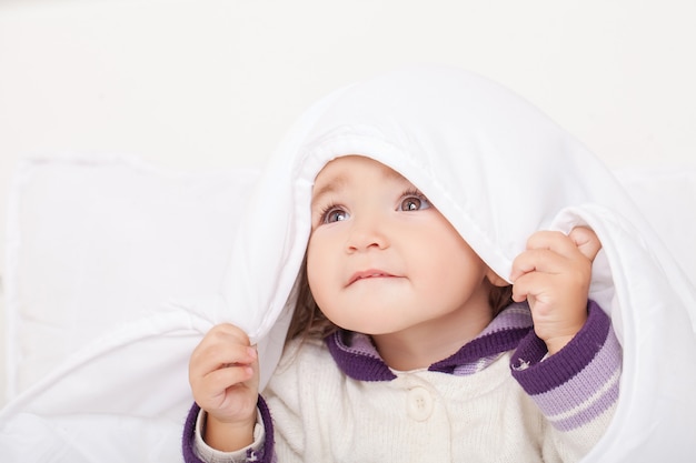 Portret dziewczynki leżącej w łóżku pod piórami