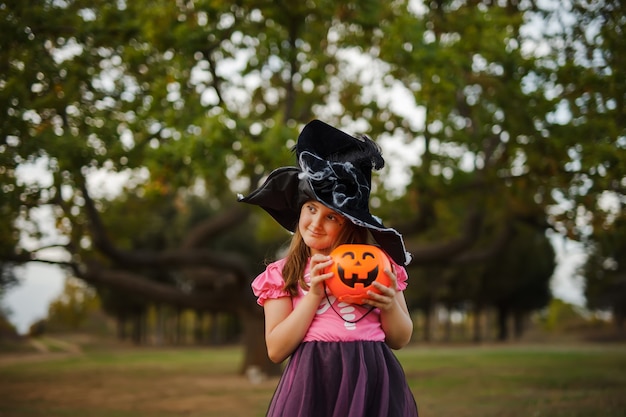 Portret dziewczynki w kostiumie czarownicy na Halloween i czarnym kapeluszu