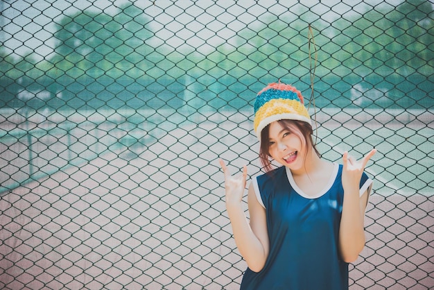 Portret dziewczyny hipster pozuje do zrobienia zdjęcia na ogrodzeniu