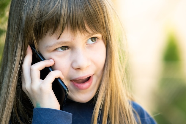 Portret Dziewczyny ładne Dziecko Z Długimi Włosami Rozmawia Przez Telefon Komórkowy. Małe Dziecko Kobiece Komunikacji Za Pomocą Smartfona. Koncepcja Komunikacji Dzieci.