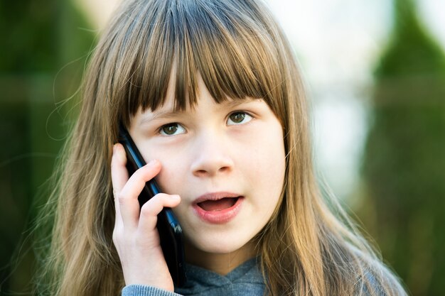 Portret dziewczyny ładne dziecko z długimi włosami rozmawia przez telefon komórkowy