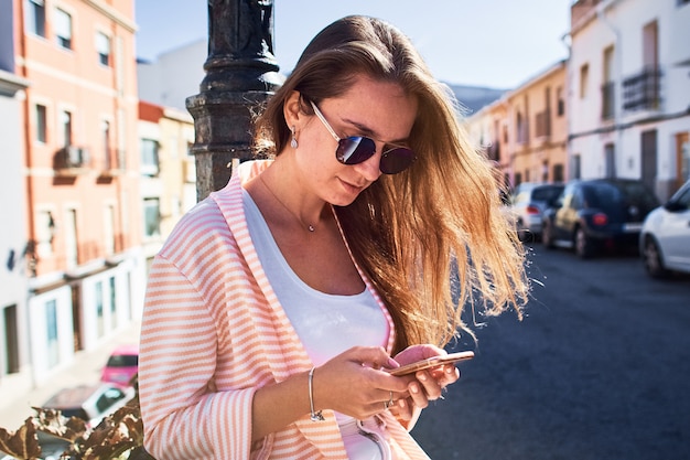 Portret Dziewczyny Odprowadzenie I Writing Wiadomości Na Telefonie Komórkowym Na Ulicie