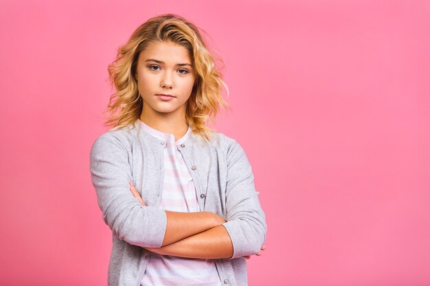 Portret dziewczyny poważne blondynka dziecko na białym tle nad różowym tle.