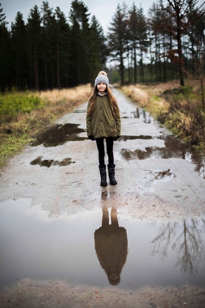 Portret dziewczyny stojącej na mokrej drodze