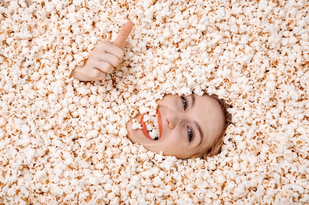 Portret dziewczyny w popcorn. Młoda kobieta pochowana w popcorn.