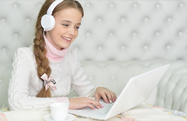 Zdjęcie portret dziewczyny w słuchawkach za pomocą laptopa