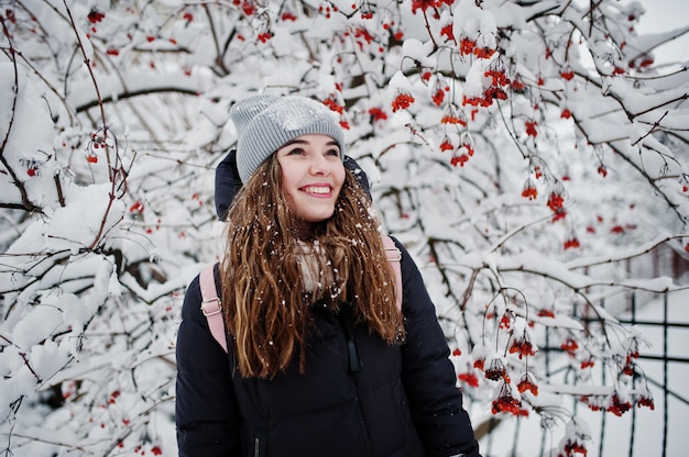 Portret dziewczyny w zimowy śnieżny dzień w pobliżu pokryte śniegiem drzewa.