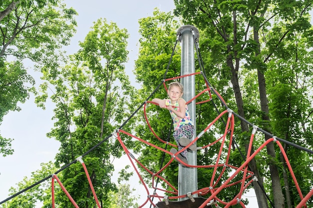 Portret dziewczyny wspinającej się na szczyt po linach w parku rekreacyjnym