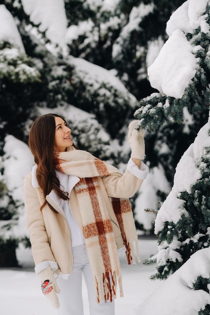 Portret dziewczyny z długimi włosami w rękawiczkach w lesie zimą Śnieżna zima