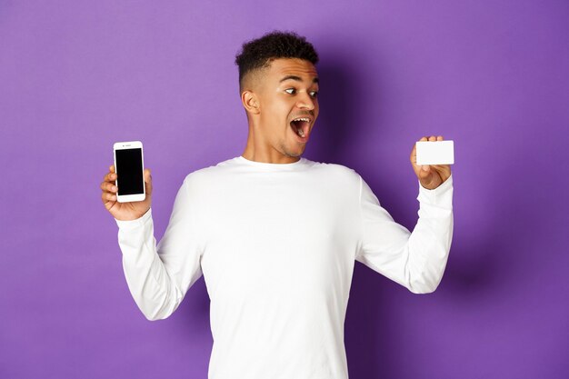 Portret Ekspresyjny Młody Człowiek Posiadający Telefon I Kartę Kredytową