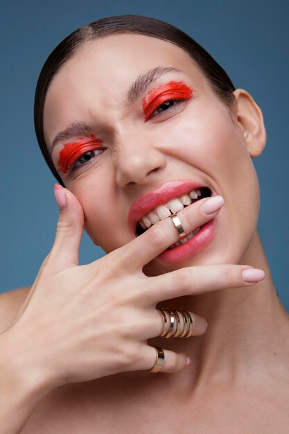 Portret eleganckiej młodej kobiety z czerwonym jasnym makijażem na niebieskim tle. Moda uroda