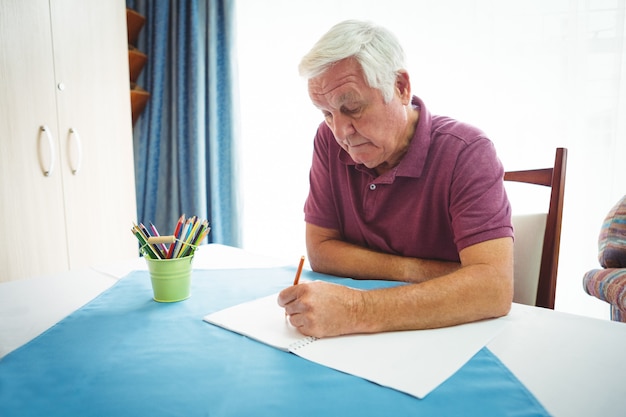 Portret emeryta mężczyzna pisze na białym papierze