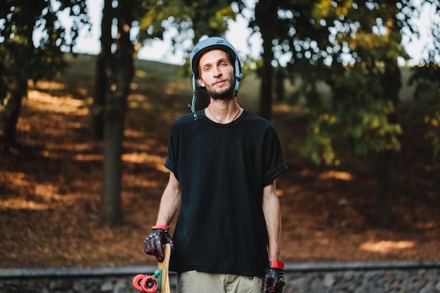 Portret faceta w niebieskim kasku z longboardem. Wysokiej jakości zdjęcie