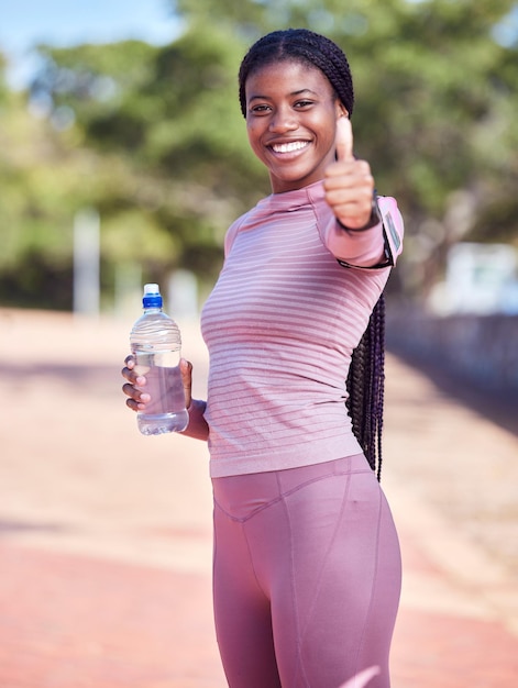 Portret fitness i czarna kobieta aprobuje wodę do ćwiczeń na świeżym powietrzu w celach zdrowotnych i odnowy biologicznej Motywacja do treningu sportowego i szczęśliwa lekkoatletka gestem ręki dla sukcesu lub wsparcia