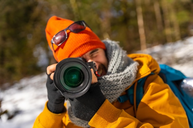 Portret fotografa robiącego zimowe zdjęcia w górach ze śniegiem podczas trekkingu z plecakiem