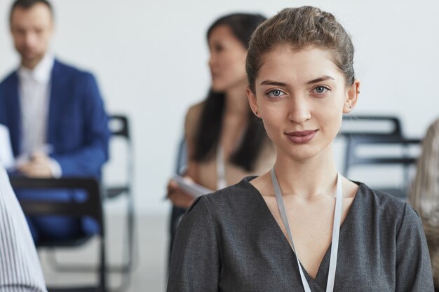 Portret Głowy I Ramion Młodej Bizneswoman Patrząc Na Kamerę Siedząc Na Widowni Na Konferencji Biznesowej Lub Seminarium, Kopia Przestrzeń