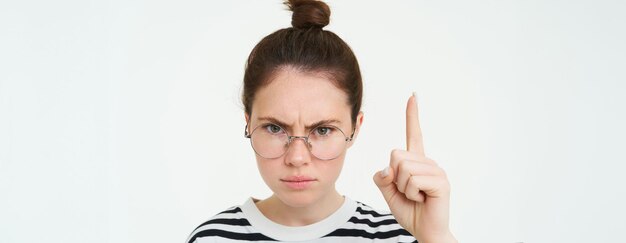 Zdjęcie portret gniewnej, poważnej kobiety w okularach, wskazującej palcem w górę, pokazującej, że jest ważna