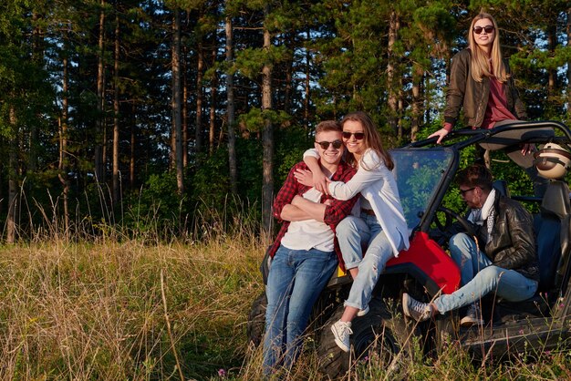 portret grupy młodych szczęśliwych ludzi cieszących się pięknym słonecznym dniem podczas jazdy samochodem terenowym buggy po górskiej naturze