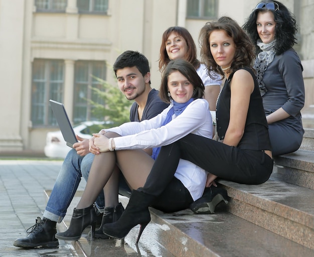 Portret grupy studentów siedzących przed uniwersytetem