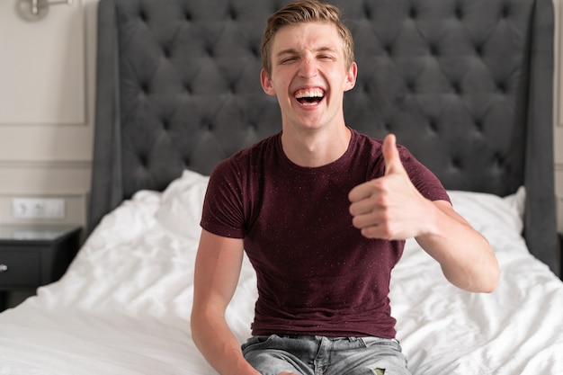 Portret Headshot szczęśliwy Kaukaski młody człowiek siedzi w domu na łóżku