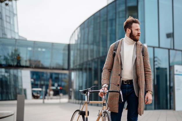 Portret hipstera biznesmena z rowerem za pomocą smartfona Lokalizacja centrum biznesowego