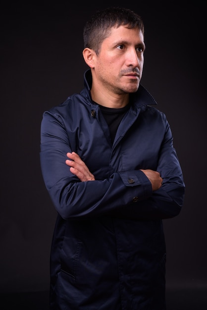 Portret Hispanic biznesmena przeciw czarnej ścianie