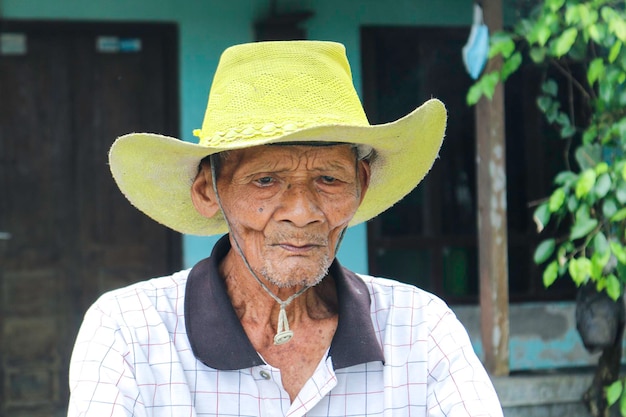 Portret indonezyjskiego starego rolnika w żółtym kapeluszu ze starym rowerem