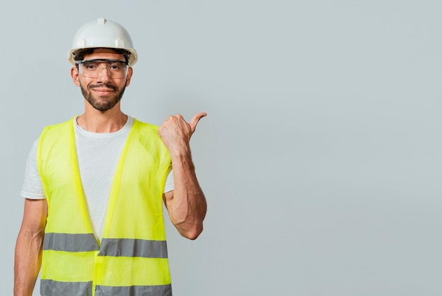 Portret inżyniera mężczyzny wskazującego na bok Pracownik budowlany z kamizelką wskazującą na reklamę Inżynier mężczyzna wskazujący na bok Inżynier budowniczy wskazujący palcem w prawo na białym tle