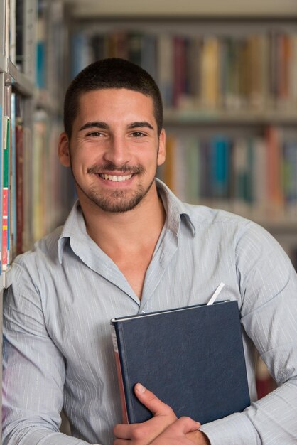 Portret kaukaskiego mężczyzny, studenta college'u w bibliotece, niewielka głębia ostrości