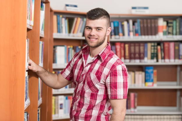 Portret kaukaskiego mężczyzny, studenta college'u w bibliotece, niewielka głębia ostrości