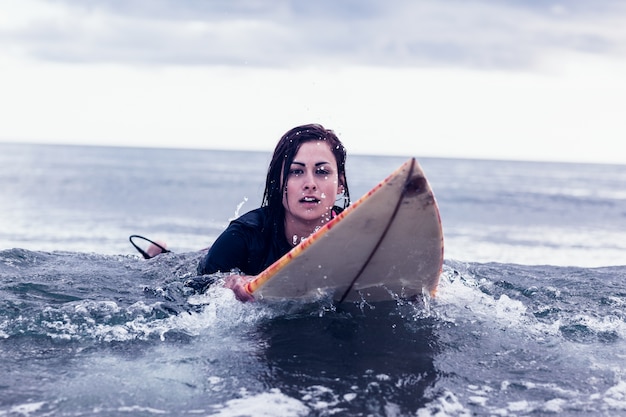 Portret kobieta pływa nad surfboard w wodzie