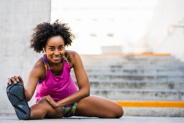 Portret kobiety afro sportowiec, rozciąganie nóg przed ćwiczeniami na świeżym powietrzu. Sport i zdrowy tryb życia.