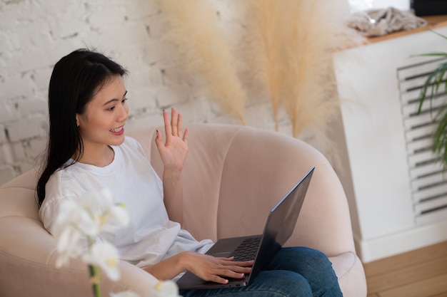 Portret kobiety azjatyckich korzystających z laptopa w mieszkaniu wnętrze pokój dzienny. Koncepcja strumienia wideorozmowy webinarowej.