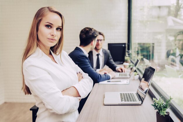 Zdjęcie portret kobiety biznesmenki siedzącej z kolegami na tle w biurze