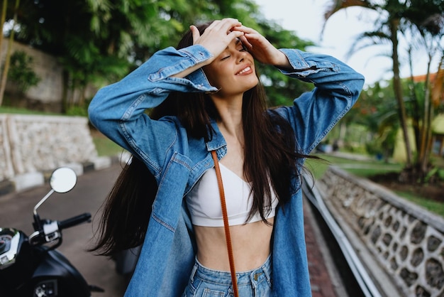 Portret kobiety brunetka uśmiecha się z zębami chodzącymi na zewnątrz na tle palm w tropikach letnie wakacje i rekreacja na świeżym powietrzu beztroski styl życia niezależnego studenta