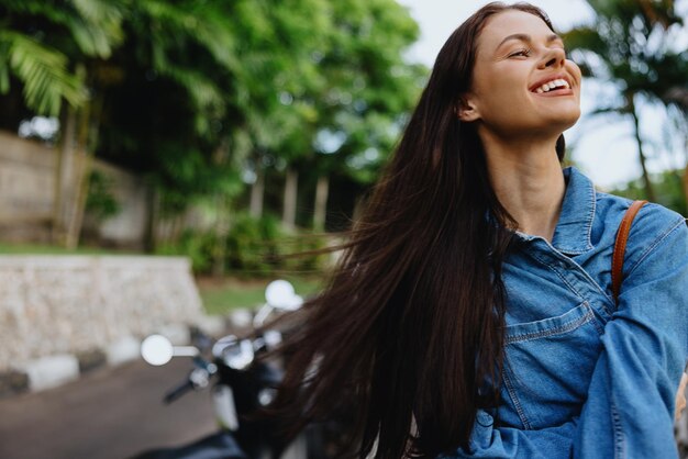 Portret kobiety brunetka uśmiecha się z zębami chodzącymi na zewnątrz na tle palm w tropikach letnie wakacje i rekreacja na świeżym powietrzu beztroski styl życia niezależnego studenta