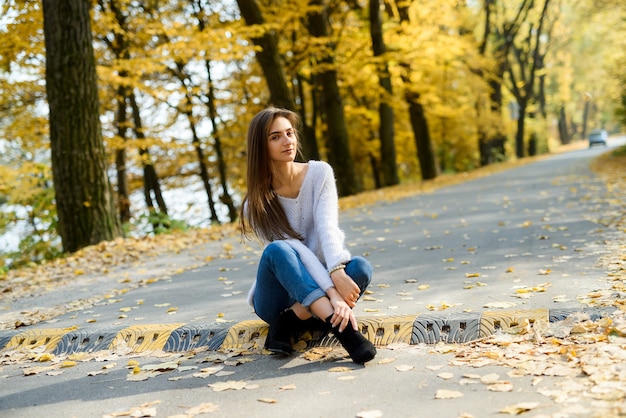 Portret kobiety brunetka w casual w jesienny park. Żółte kolory wokół pięknej kobiety