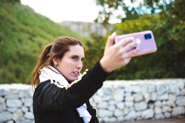 Portret kobiety fotografującej telefonem komórkowym