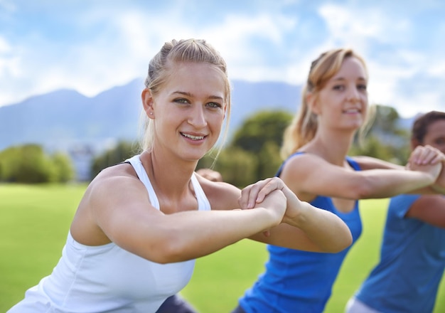 Zdjęcie portret kobiety i przyjaciół z przysiadami do ćwiczeń fitness lub treningu na świeżym powietrzu na boisku sportowym z uśmiechem współpraca sportowca i twarz z szczęściem do treningu aktywności fizycznej lub wellness