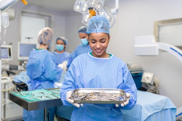 Portret kobiety-pielęgniarki chirurga LUB członka personelu ubranego w fartuch chirurgiczny, maskę i siatkę do włosów w sali operacyjnej szpitala