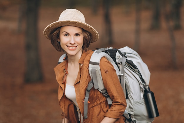 Portret kobiety podróżnik patrzeje zadziwiającego las z plecakiem, podróżuje pojęcie