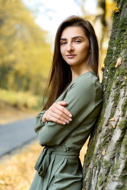 Portret kobiety. Portret kobiety brunetka w jesiennym parku na sobie oliwkową sukienkę